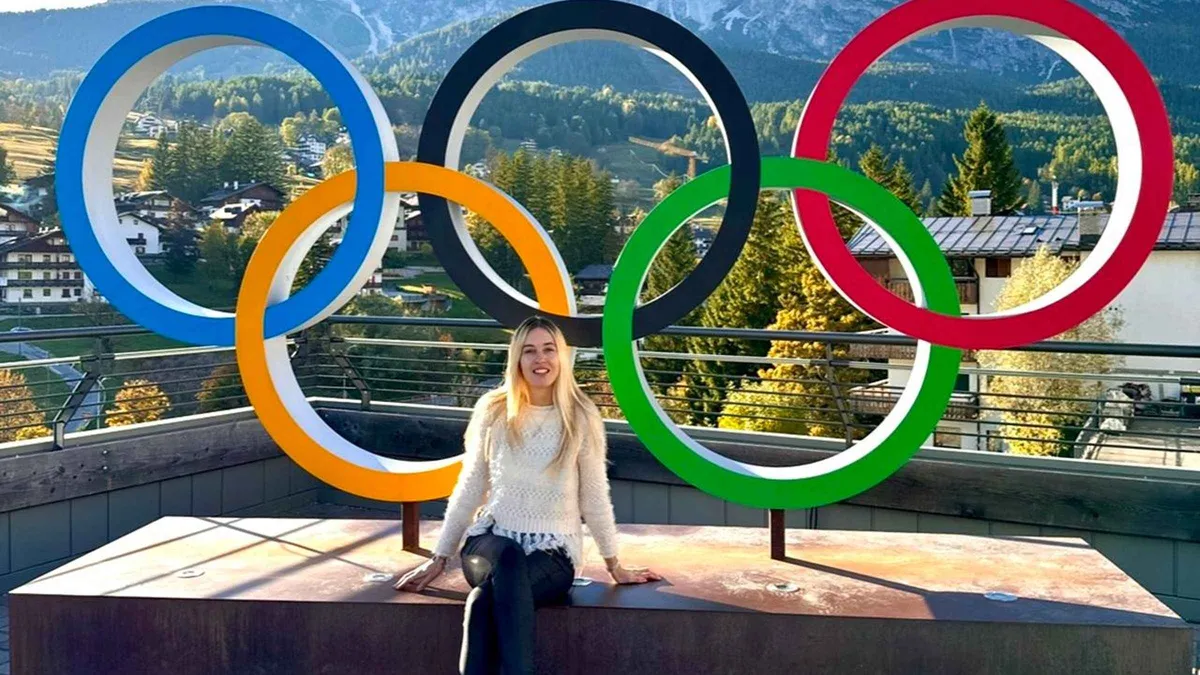 A traveler sitting under the giant Olympic rings on a terrace in Cortina d'Ampezzo