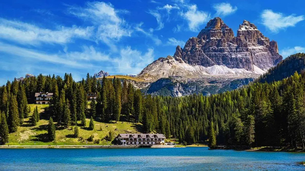 Lake Misurina and its large lakeside hotel under a pointed snow-streaked peak