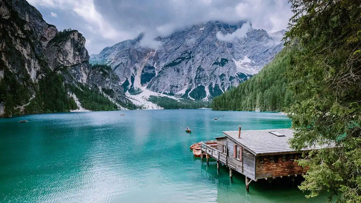 The Lake Braies boathouse jetty on emerald water beneath grey cliffs and cloud