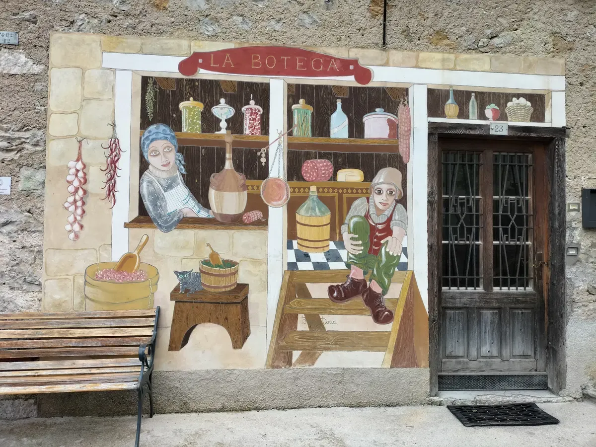 A painted shop-front mural named La Botega on a house wall in Cibiana di Cadore